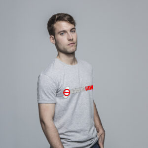 A person standing against a gray background is wearing the "Raw is Law" light gray T-shirt adorned with bold red text.