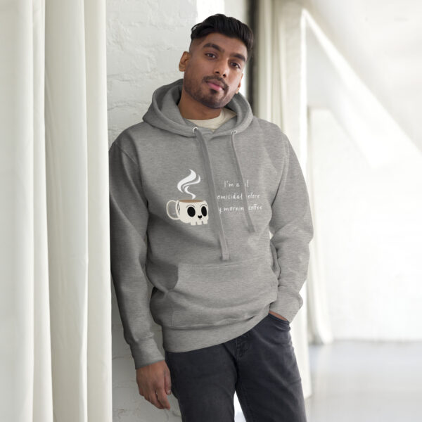 An individual wearing the "I'm a Bit Homicidal Before My Morning Coffee" hoodie, featuring a steaming cup design, stands by a white wall in a brightly lit room.