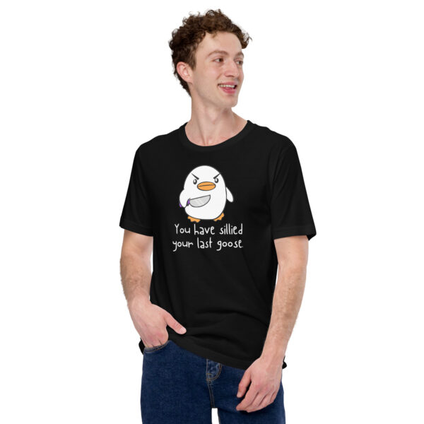 A person smiling and standing with one hand in their pocket, dressed in the "You Have Sillied Your Last Goose" black T-shirt featuring a cartoon bird.