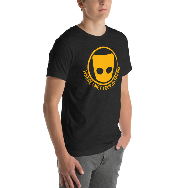 A person wearing a black T-shirt featuring a yellow mask logo and the title "Where I Met Your Husband.