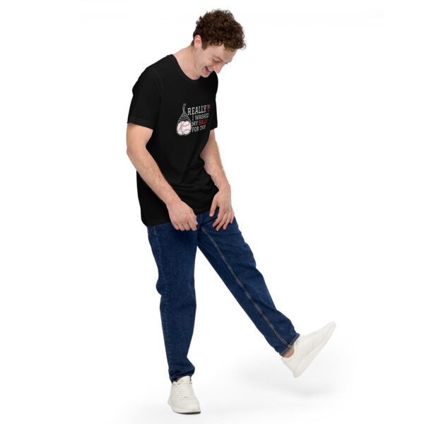 A person in a "Really?! I washed my balls for this!" black graphic T-shirt and blue jeans is playfully extending one leg while looking down.