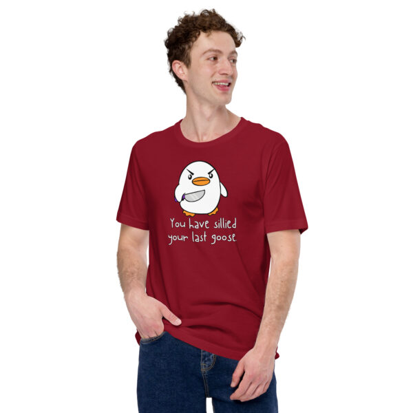 A person in a red T-shirt featuring a cartoon penguin and the phrase "You Have Sillied Your Last Goose" smiles while gazing to the side.