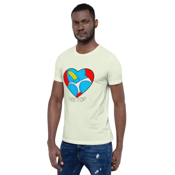 A man is dressed in a light-colored T-shirt adorned with a large heart design showcasing a cartoon bear, accompanied by the text "His Top" underneath. He has paired it with dark jeans.