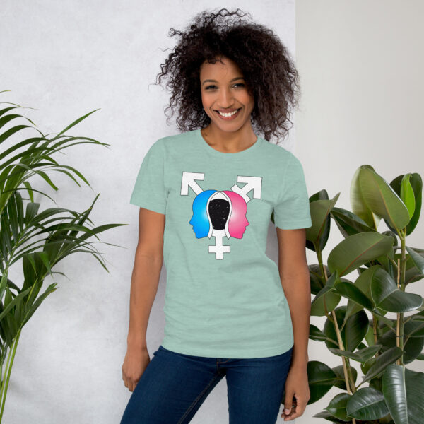 A smiling person wearing the "Beyond the Binary" light green T-shirt with a gender symbol design, standing between two potted plants.