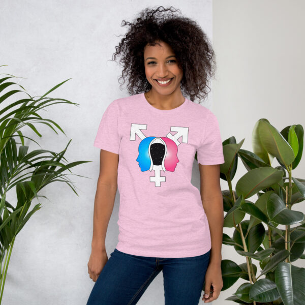 A person wearing the "Beyond the Binary" pink shirt, featuring silhouettes and gender symbols, stands beside a green plant.