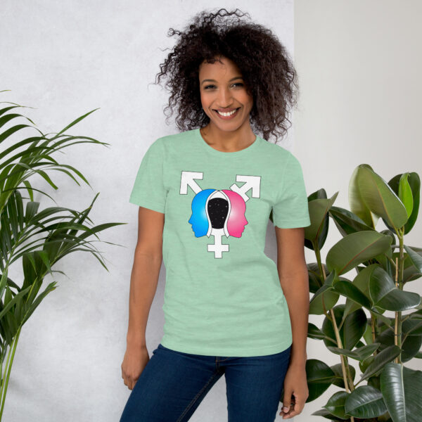 A person wearing the "Beyond the Binary" design T-shirt, featuring gender symbols and a colorful pattern, stands between two green plants, smiling.