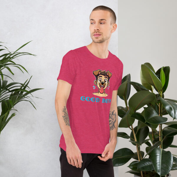 A man wearing a red "Good Boy" t-shirt featuring a cartoon dog design stands near a potted plant.