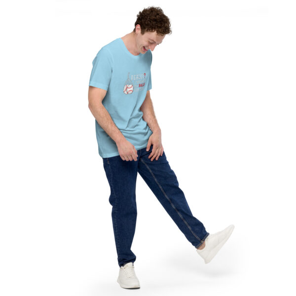 Wearing a light blue "Really?! I washed my balls for this!" T-shirt, jeans, and white sneakers, the person stands with one leg slightly lifted, looking down with a smile.