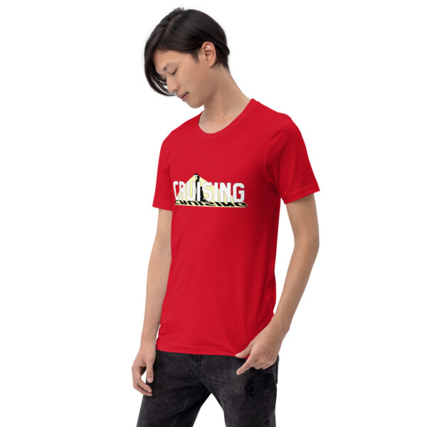 A person wearing a "Cruising" t-shirt in red paired with black jeans stands looking down.