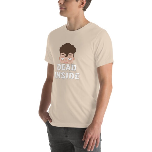 A person is wearing a beige "Dead Inside" t-shirt featuring a cartoon face.