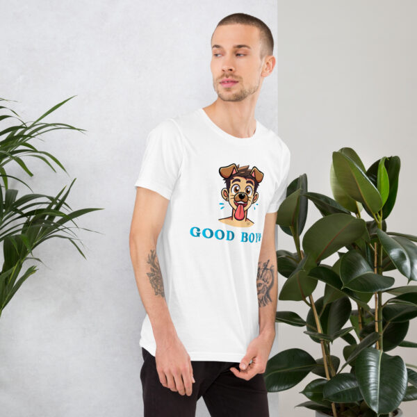 A man wearing a white "Good Boy" t-shirt featuring a cartoon dog is standing beside indoor plants.