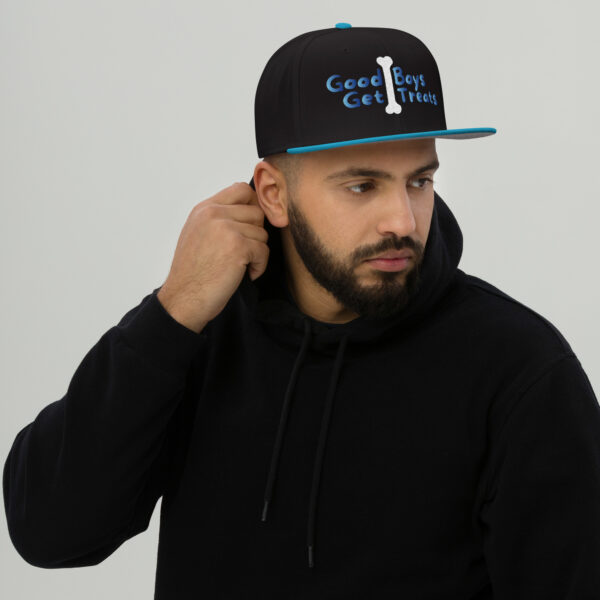 A bearded man in a black hoodie and a Snapback Hat adorned with the text "Good Boys Get Treats," looking to the side.