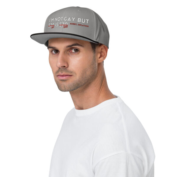 A man wearing the "I'm Not Gay Snapback Hat," which has text that reads "I'M NOT GAY BUT $20 IS $20 SORRY, INFLATION," along with a white shirt.