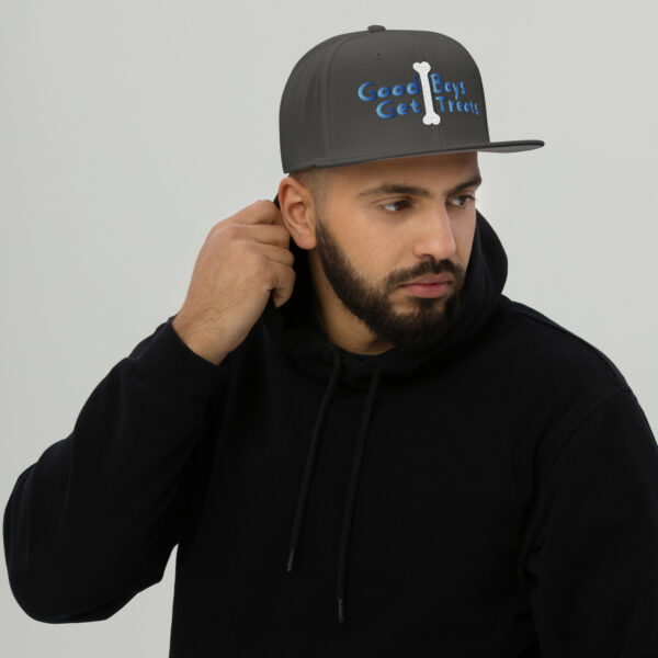 A man wearing a black hoodie adjusts his gray Snapback Hat featuring the phrase "Good Boys Get Treats" along with a bone graphic, set against a plain background.