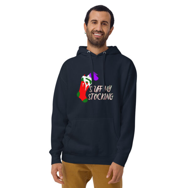 A person is wearing a Unisex Hoodie featuring a vibrant stocking graphic and the text "STUFF MY STOCKING," as they stand and smile.