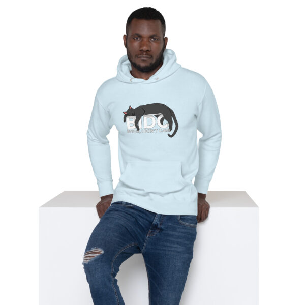 A man wearing a light blue BIDC Hoodie featuring a cat design leans against a white cube.