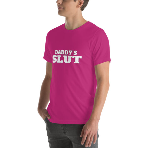 A person wearing a pink Daddy's Slut t-shirt with the text in a bold, white font.