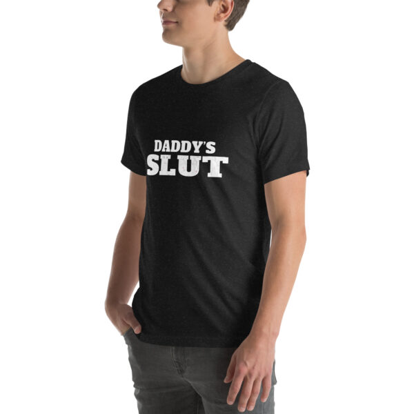 Someone wearing a black t-shirt labeled "Daddy's Slut" in white text, standing with hands in pockets.