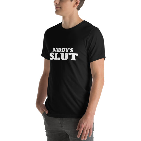 A person wearing a black T-shirt featuring the "Daddy's Slut" design in white text, standing with hands in pockets.