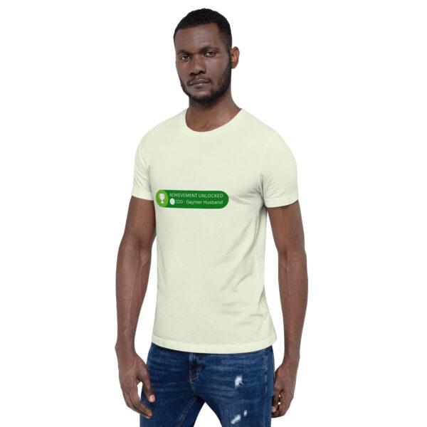 A person wearing the light green "Achievement: Gaymer Husband" T-shirt, featuring the print "+100 - Gaymer Husband," standing against a white background.