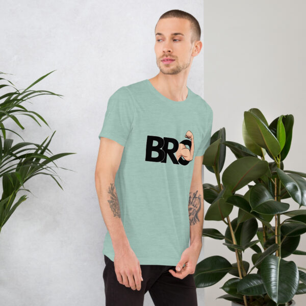 A person wearing a light green t-shirt with the name "Bro" stands near indoor plants, looking to the side.