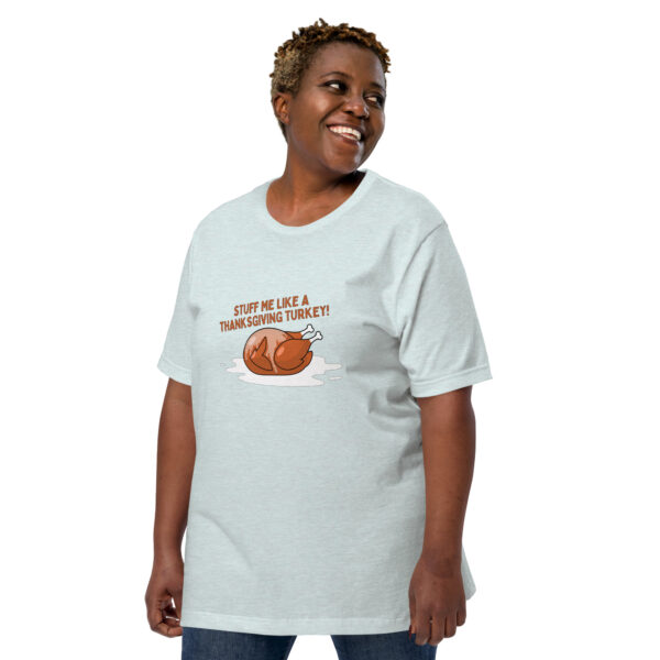 A smiling person wearing a light-colored T-shirt featuring a cartoon turkey and the text "Stuff Me," reminiscent of a Thanksgiving turkey.