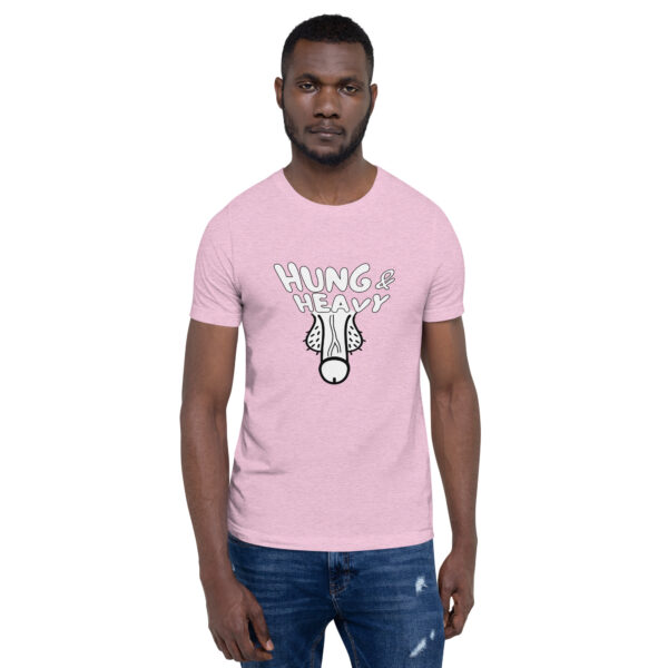 A man standing against a plain background is wearing a pink "Hung and Heavy" t-shirt featuring an illustrated graphic.