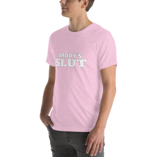 A person wearing a light pink T-shirt featuring the product "Daddy’s Slut" with the phrase displayed in white letters.