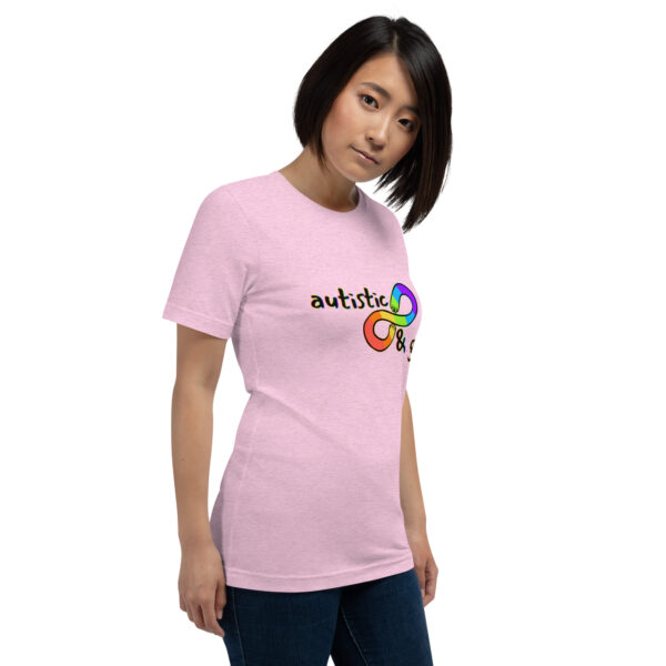 A person wearing the "Autistic & Gay" pink t-shirt, adorned with a multicolored design of interlocking infinity symbols and the word "autistic".