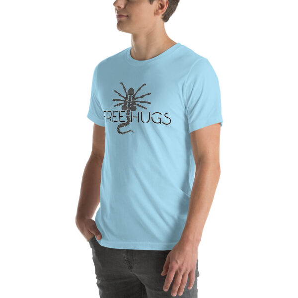 Person wearing the "Free Hugs" T-shirt in light blue, featuring a black scorpion graphic and the phrase "FREE HUGS," standing against a plain background.