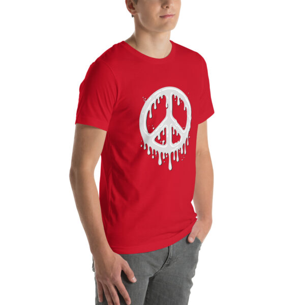 An individual is wearing the "Cum in Peace" red t-shirt, featuring a white melting peace symbol design, and standing against a plain background.