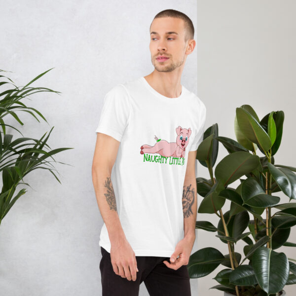 A person wearing a "Naughty Little Pig" white t-shirt featuring a pink pig design is standing beside two green plants.