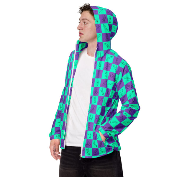 A man wearing the "Zip Up," a jacket with a vibrant green and purple checkered pattern and hood, stands with hands in his pockets, gazing to the side.