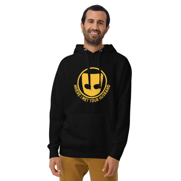 A man wearing the "Where I Met Your Husband" hoodie, featuring a black design with a yellow smiley face logo.