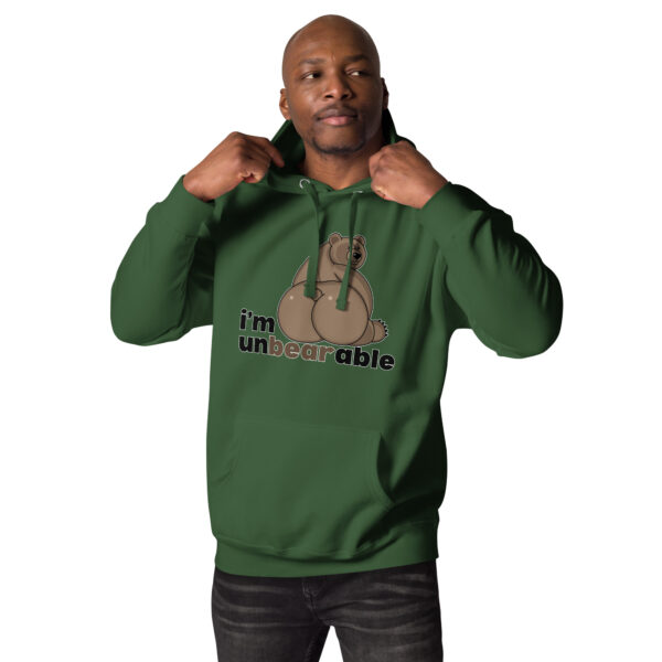 A man wearing the "I'm Unbearable" hoodie in green, featuring a bear graphic and text design, adjusts the hood while looking to the side.