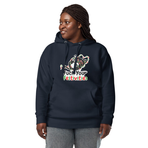 A person smiling and standing while wearing the "Fuck Your Festivities" Hoodie with a gingerbread design.