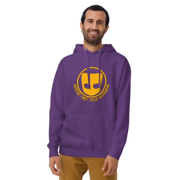 A person smiles while wearing the "Where I Met Your Husband" hoodie, featuring a purple color with a yellow emblem and text.