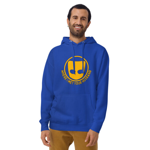 A man in a blue "Where I Met Your Husband" hoodie, featuring a musical note design, stands against a white backdrop.