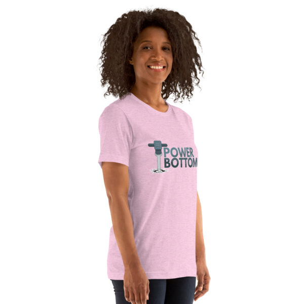 A person smiles while wearing a light pink T-shirt featuring the "Power Bottom" design and an illustration of a barbell graphic on the front.