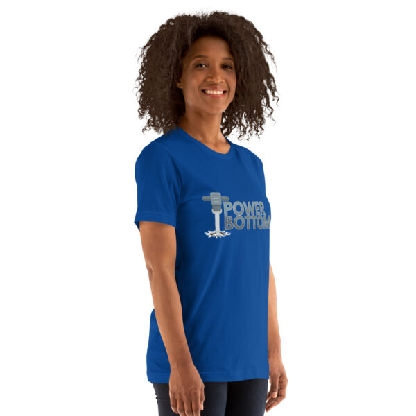 Individual in a blue "Power Bottom" T-shirt featuring a barbell design, standing and smiling.